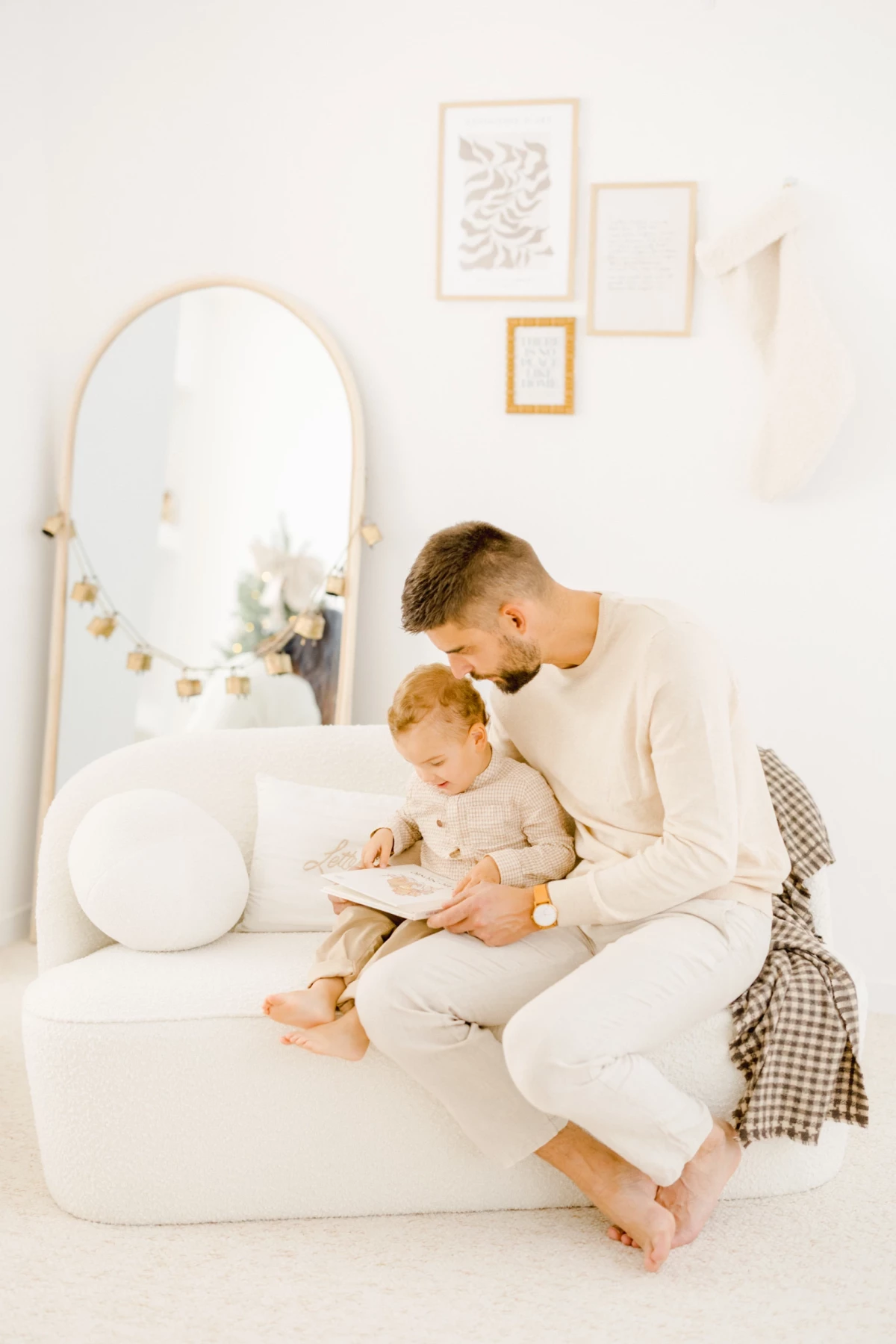 Parent lisant un livre avec son bébé dans un décor blanc chaleureux et lumineux