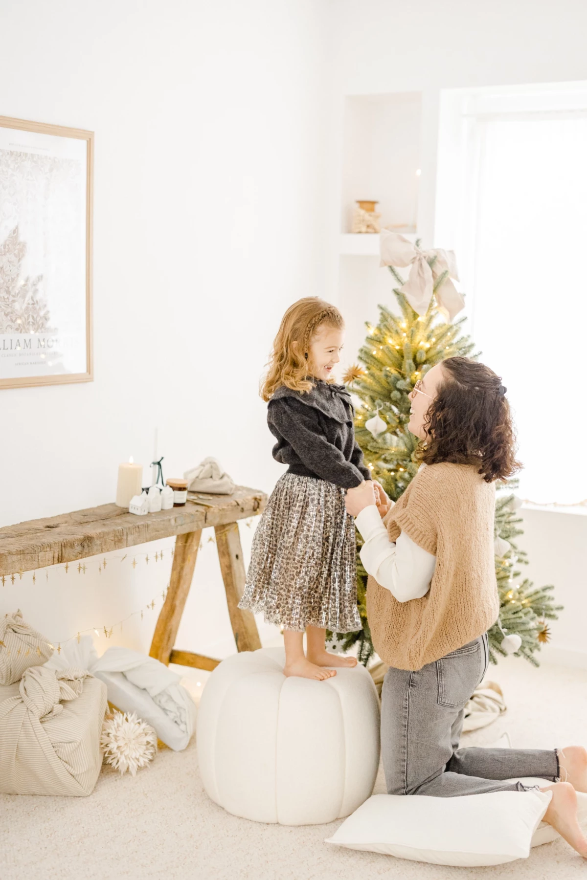Mère et fille complices près d'un sapin de Noël dans un intérieur blanc lumineux