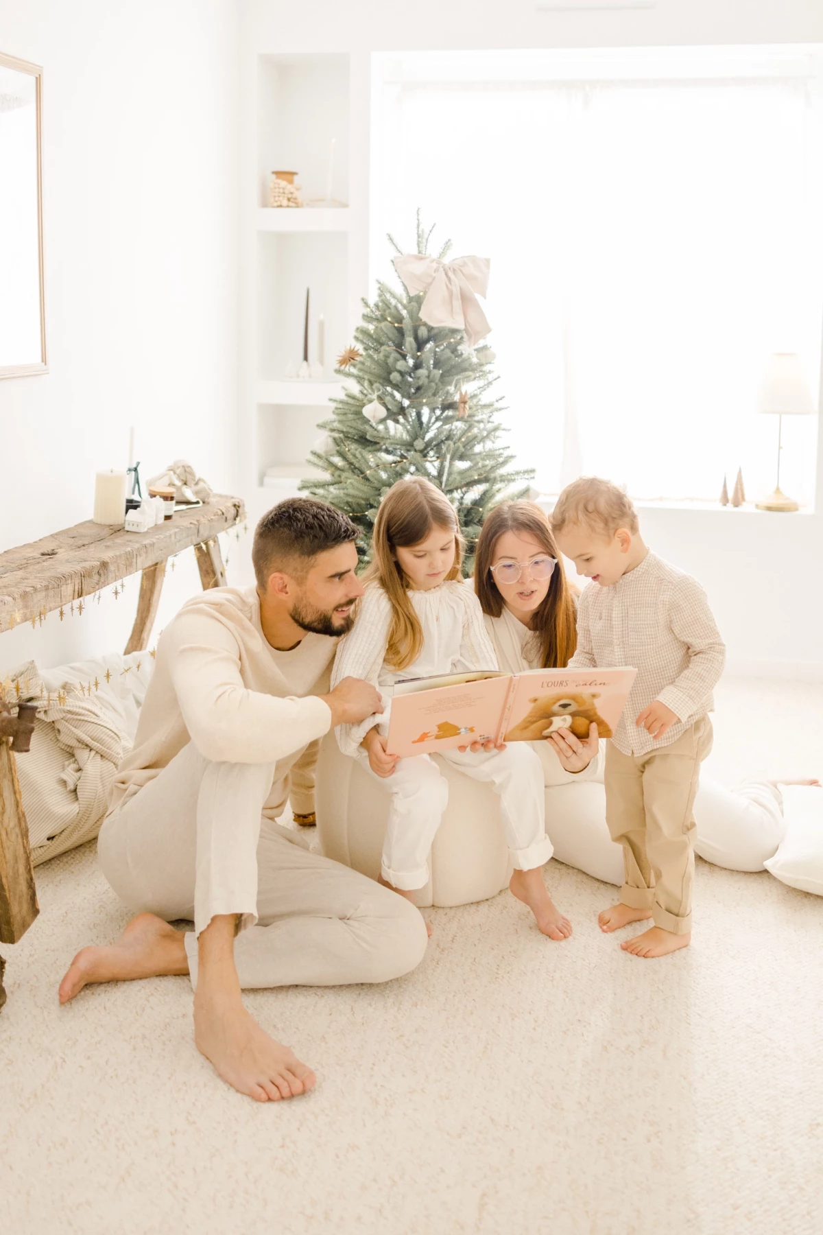 Famille réunie devant le sapin de Noël, parents et enfants regardant ensemble un album photo