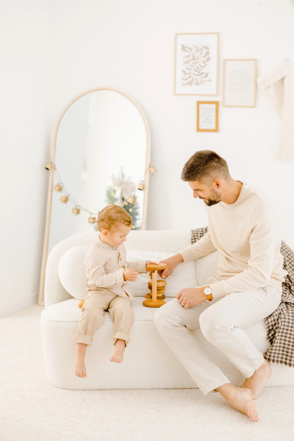 Père et fils jouant ensemble avec des blocs en bois sur un lit blanc dans une chambre épurée