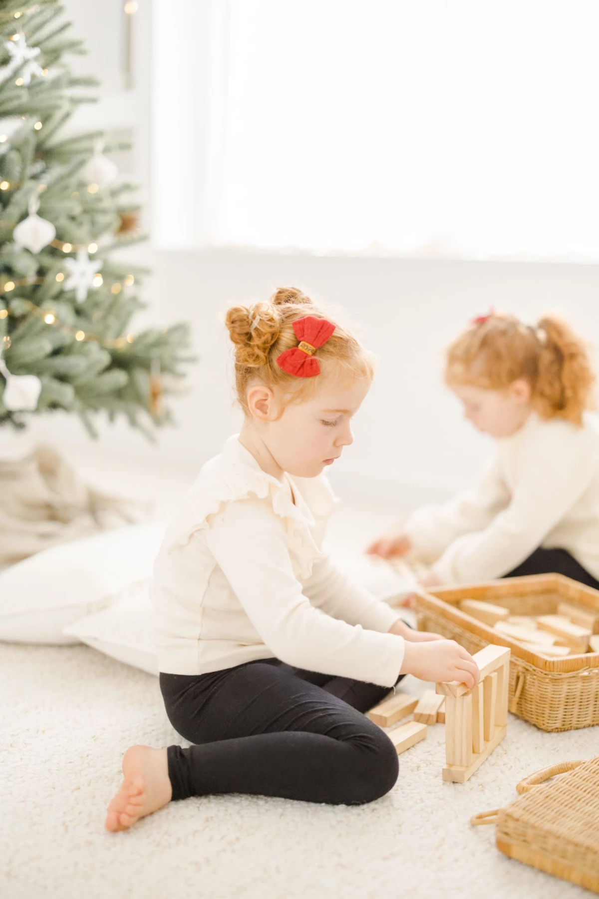 Enfant jouant avec des blocs de bois naturel près d'un sapin de Noël décoré