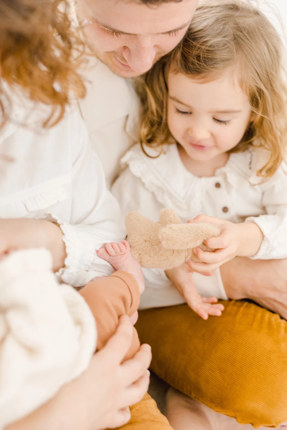 Mère avec ses deux enfants tenant un jouet en bois, moment de tendresse familiale dans une lumière douce