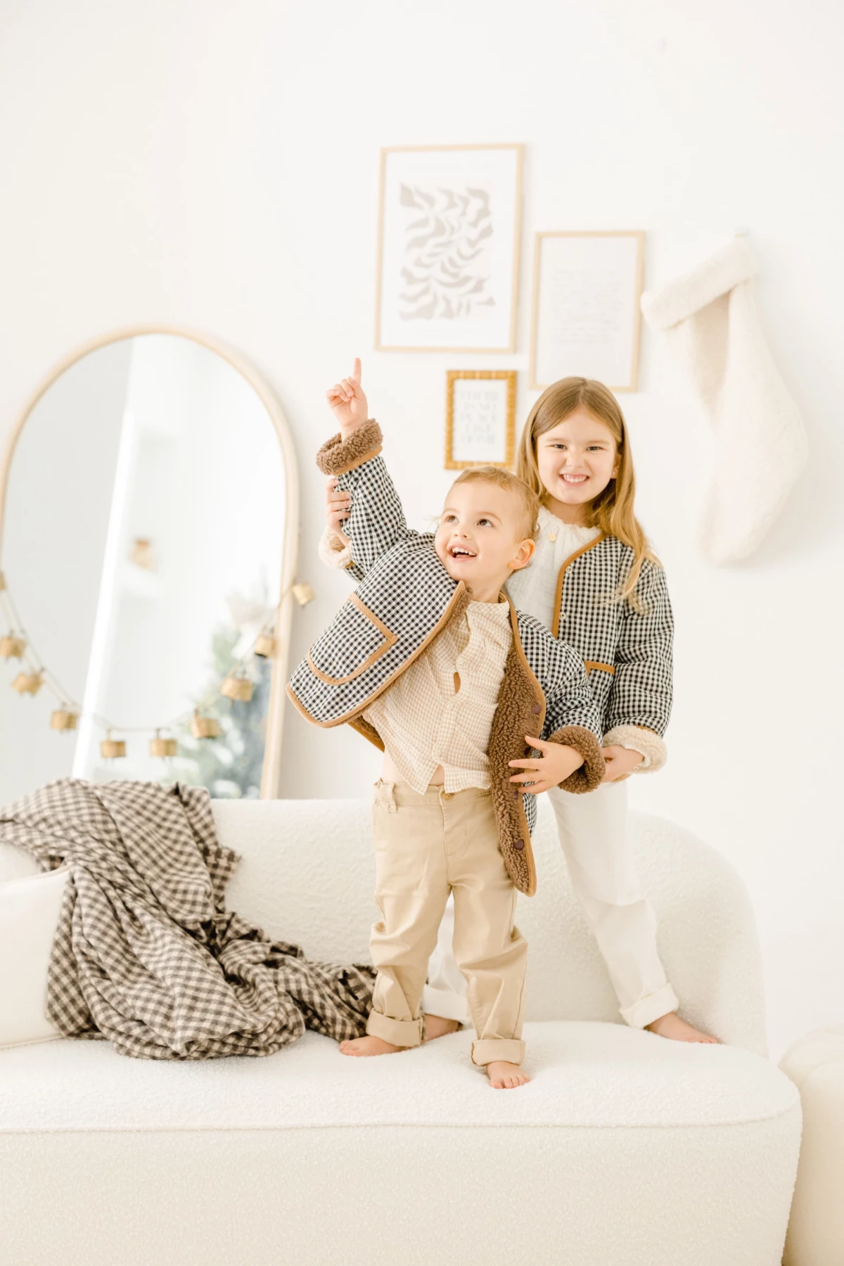 Deux enfants complices posant en studio dans une ambiance beige et blanc, avec miroir et cadres