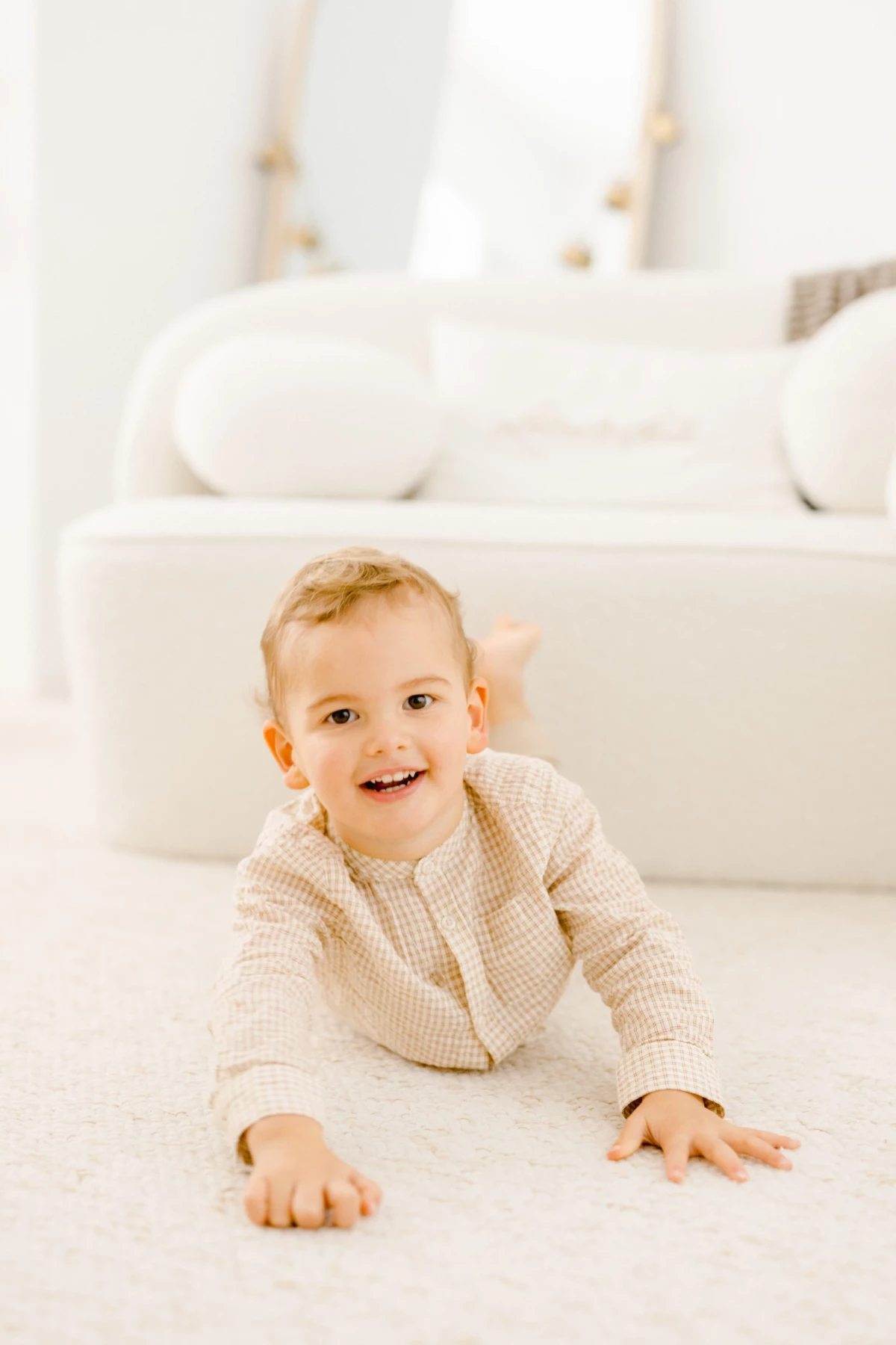 Bébé souriant assis sur un tapis blanc dans un intérieur lumineux et épuré