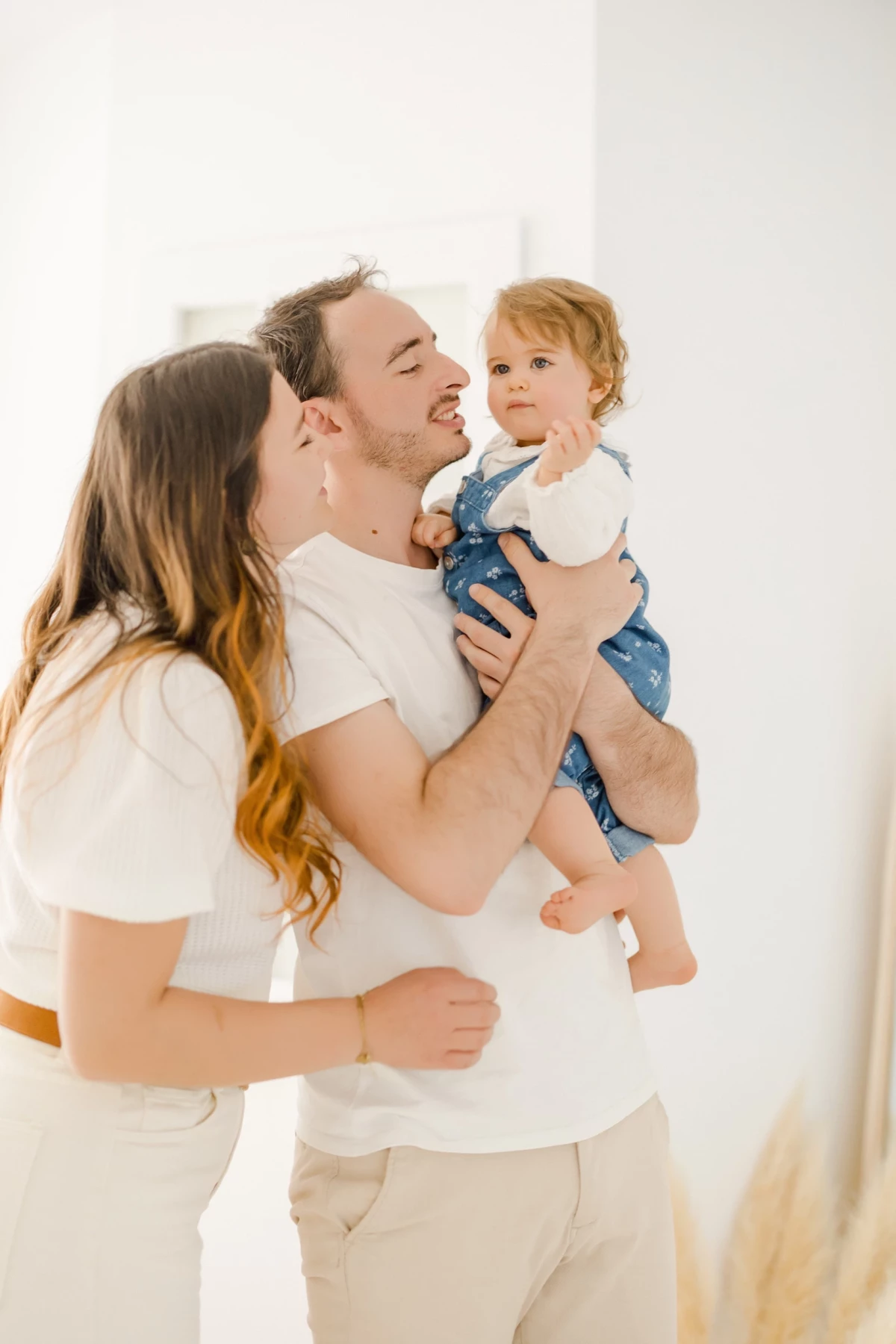 Séance famille au studio : parents et leur petite fille partagent un moment de tendresse et complicité dans une lumière douce