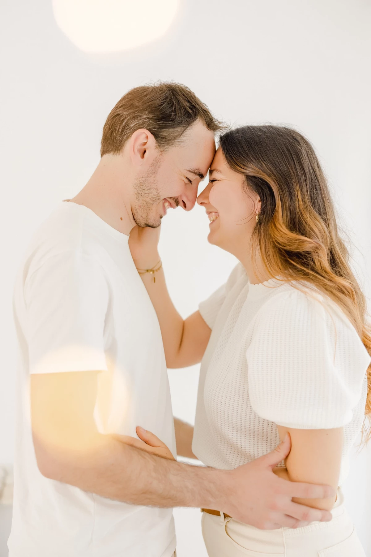 Séance couple au studio : deux amoureux se regardent tendrement dans une atmosphère lumineuse et épurée, instant de complicité naturelle