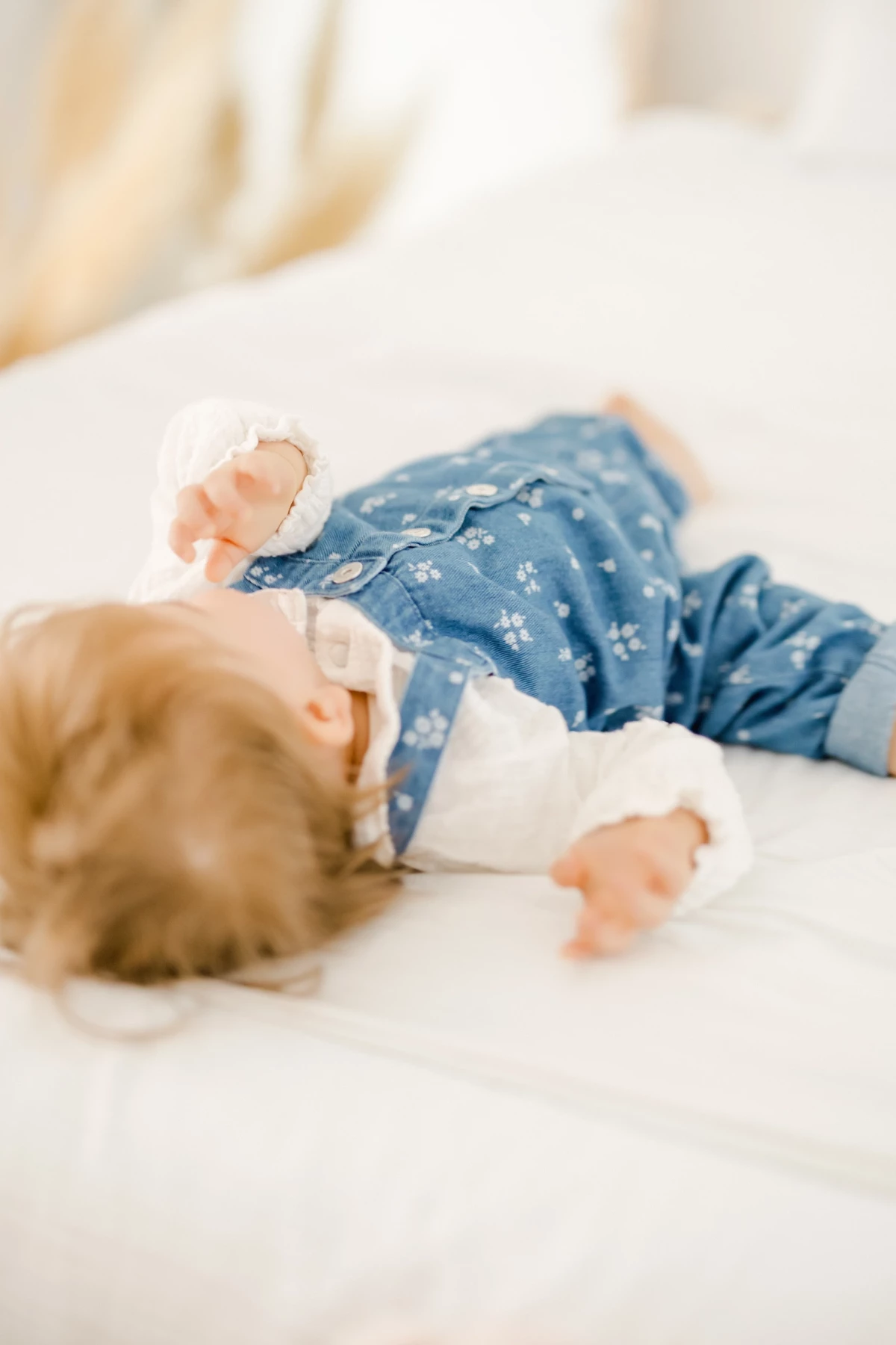 Séance bébé en studio : petit enfant allongé sur tissu blanc dans une ambiance douce et lumineuse, moment de tendresse capturé