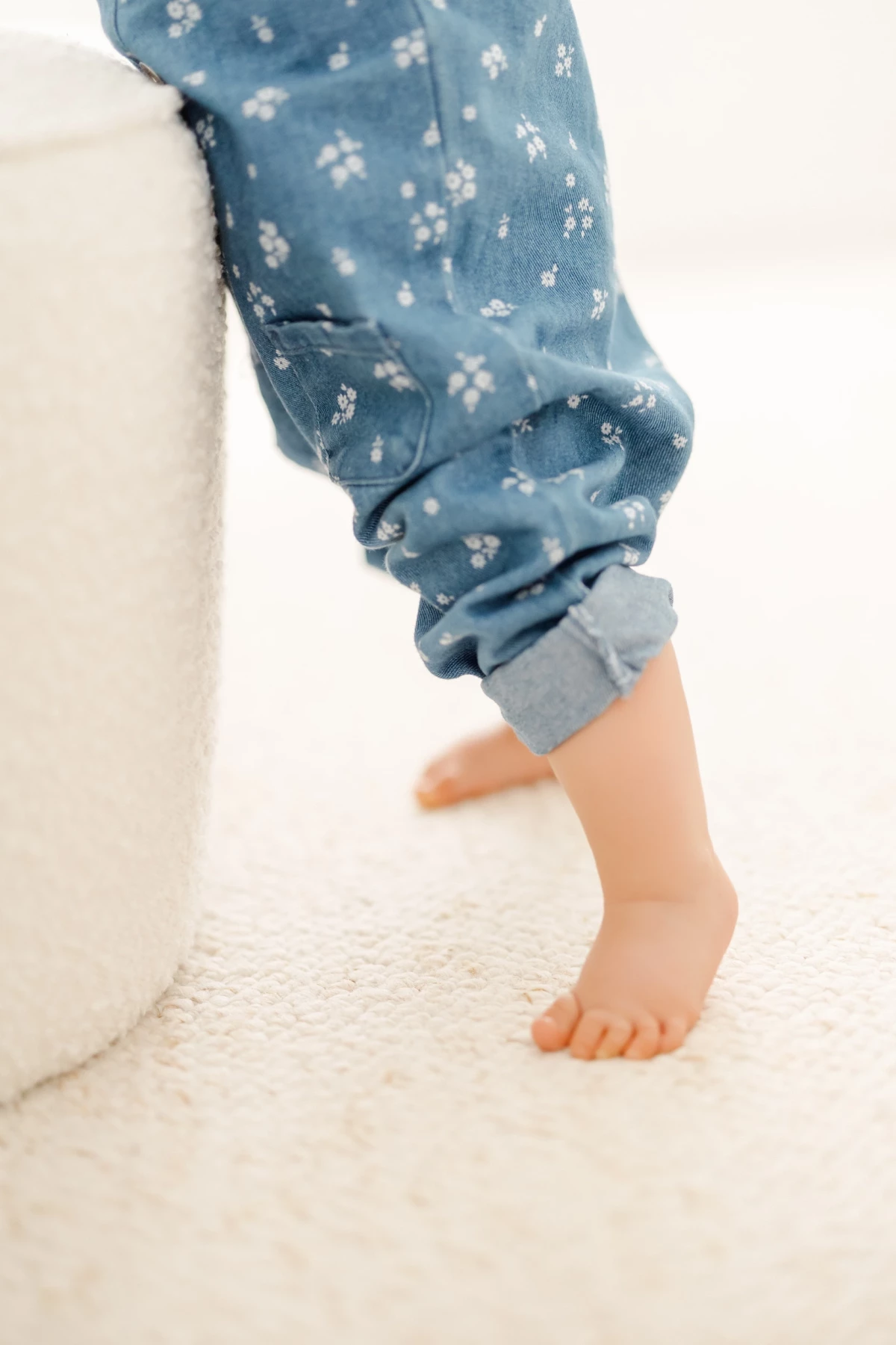 Séance famille en studio : petite fille en pyjama fleuri bleu marche pieds nus dans une ambiance douce et naturelle