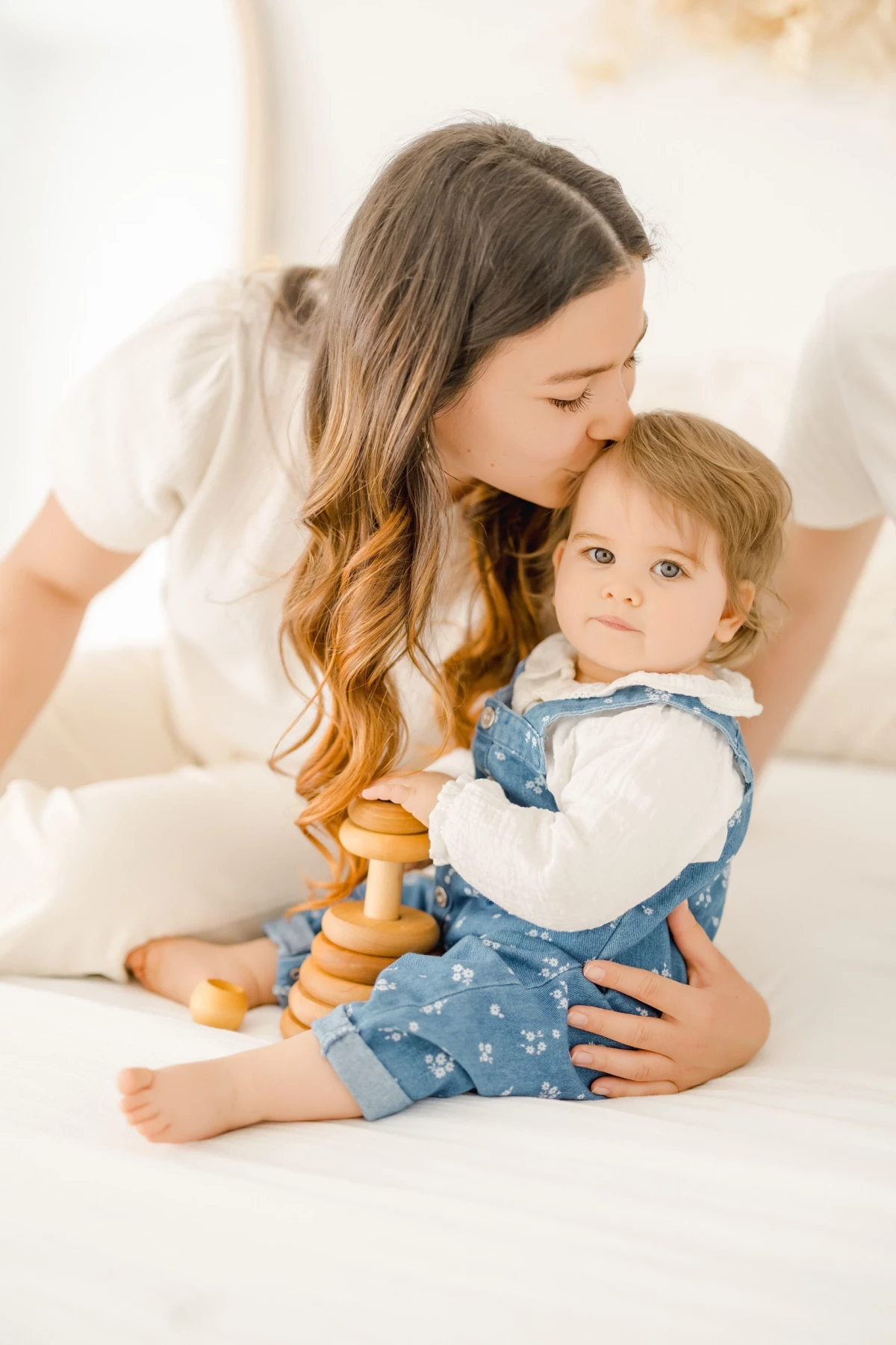 Séance famille en studio : maman enlace tendrement sa petite fille, moment de douceur et complicité naturelle sur fond lumineux