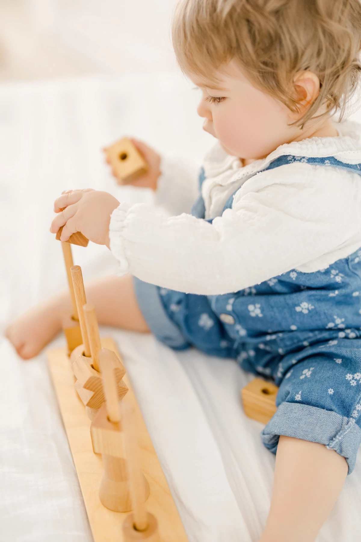 Séance famille au studio : enfant joue avec un jouet en bois dans une ambiance douce et naturelle, moment de bonheur capturé en Vendée