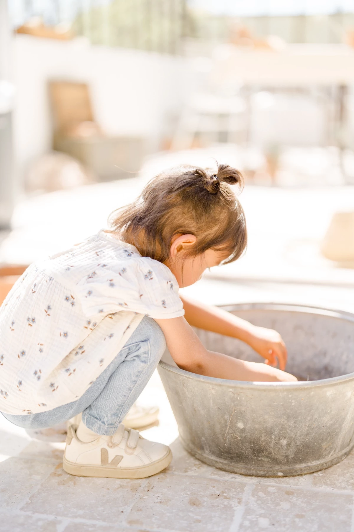 Séance famille au printemps : fillette concentrée dans une activité jardinage, instant de douceur et d'apprentissage capturé
