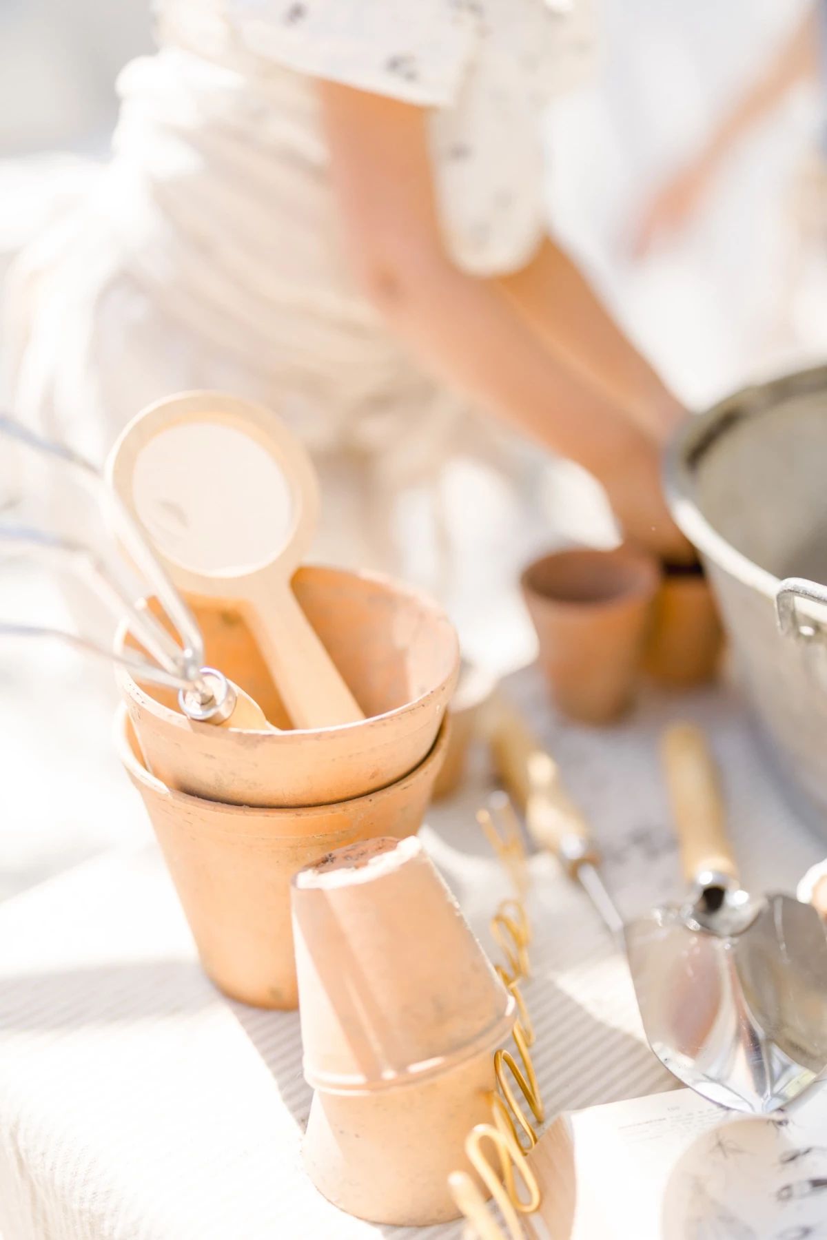 Séance famille jardinage : détails de pots en terre cuite et outils de jardin dans une lumière douce de printemps