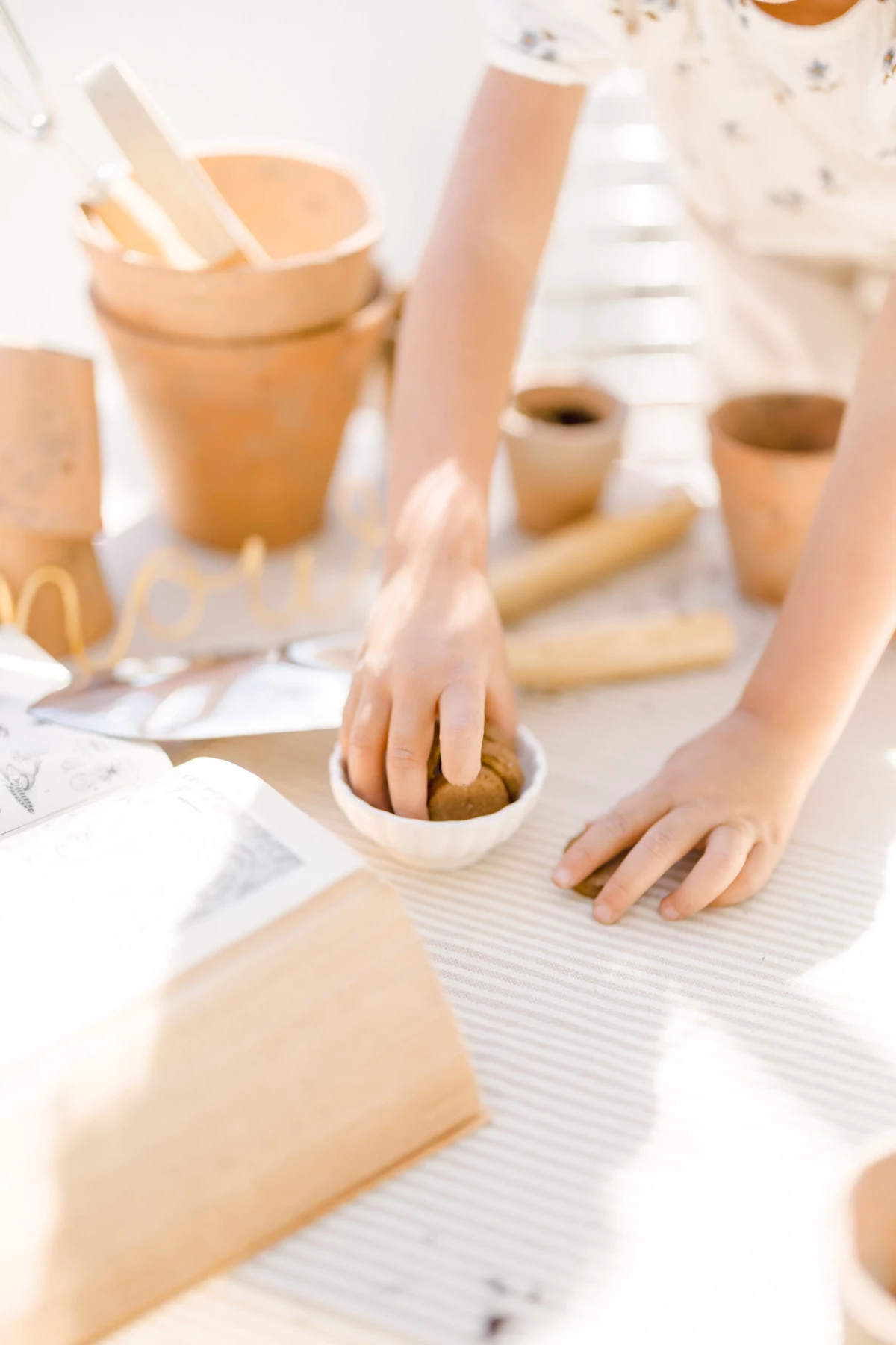 Séance famille printemps : enfant s'amuse avec des pots en terre cuite lors d'un atelier jardinage en verrière, lumière douce naturelle