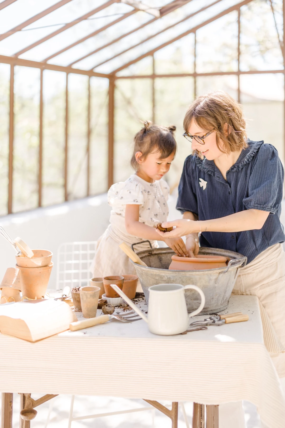 Séance famille printemps : mère et fille partagent un moment de complicité autour d'activités créatives dans une verrière lumineuse