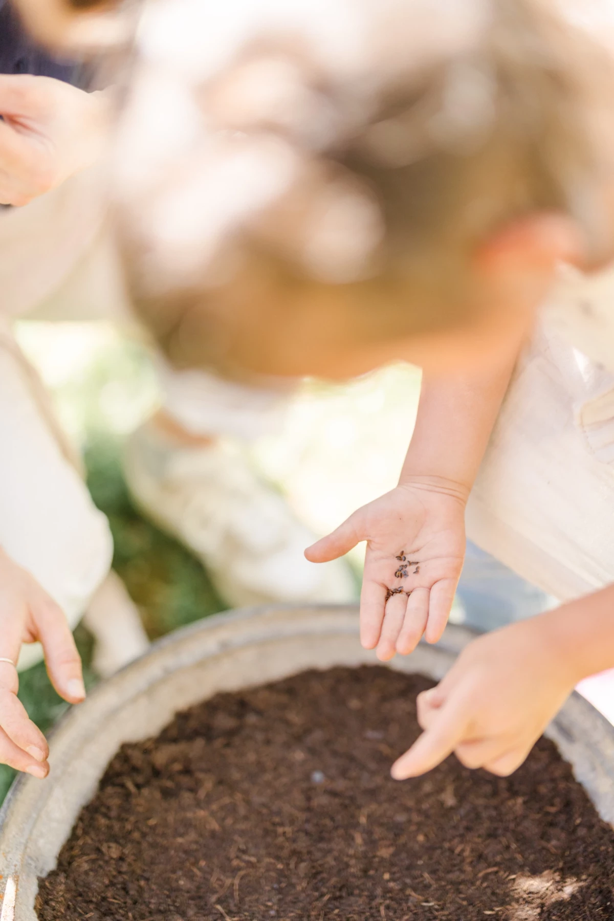 Séance famille printemps : mère et fille partagent un moment de jardinage complice dans une verrière lumineuse en Vendée