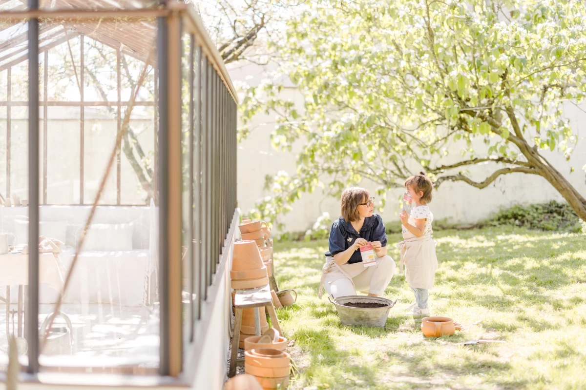 Séance famille en extérieur : mère et fille partagent un moment de complicité au jardin, lumière douce de printemps, Vendée