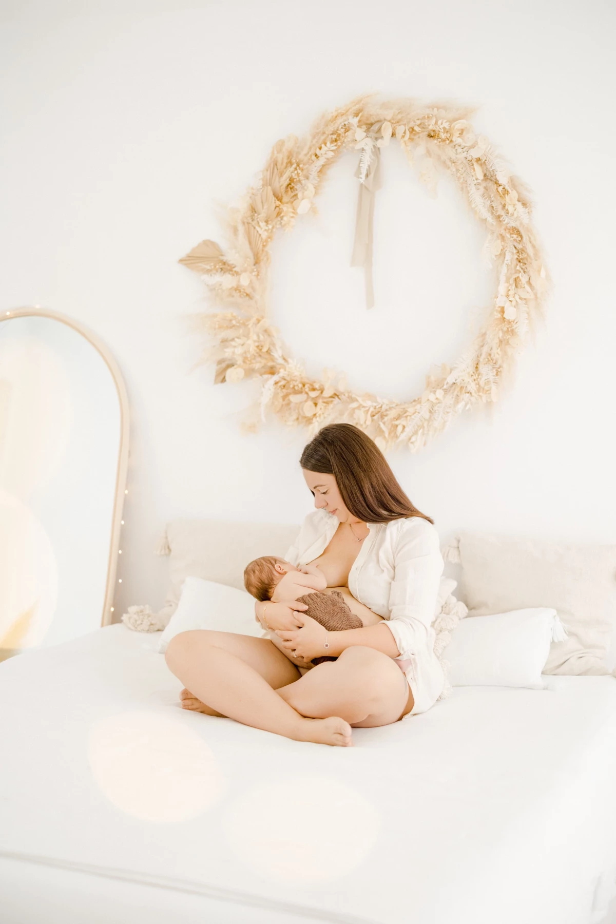 Séance allaitement en studio : maman allaite son nouveau-né en peau à peau dans une ambiance de douceur et lumière naturelle en Vendée