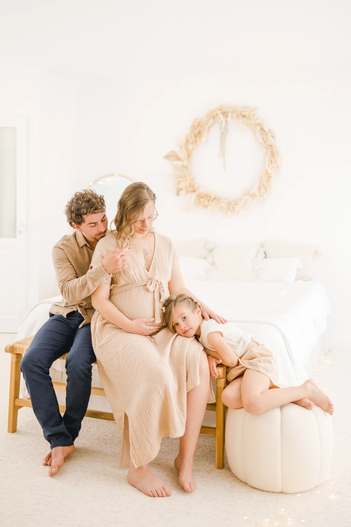 Séance grossesse en famille au studio : parents et enfant réunis dans la douceur d'un instant suspendu, lumière naturelle et décor épuré