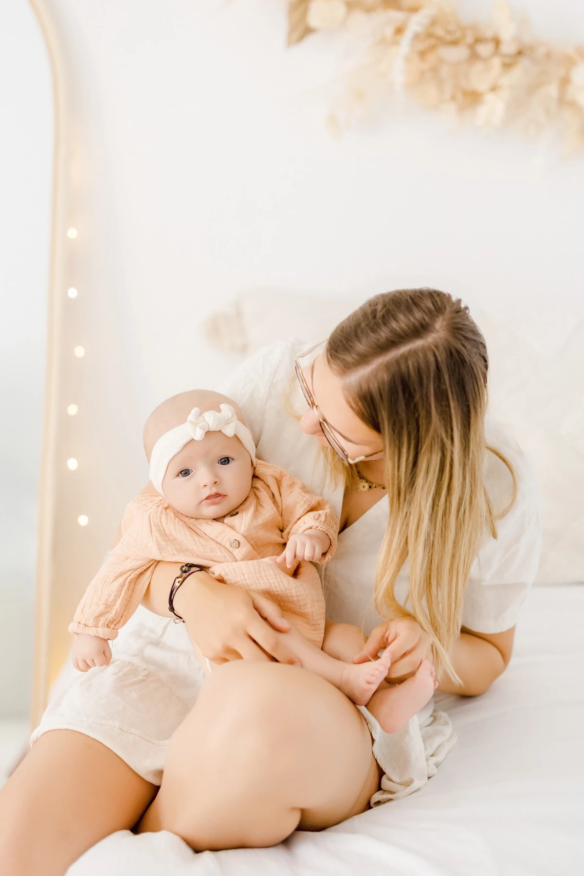 Séance naissance en studio : maman et sa petite fille de 4 mois partagent un moment de tendresse dans une lumière douce et naturelle