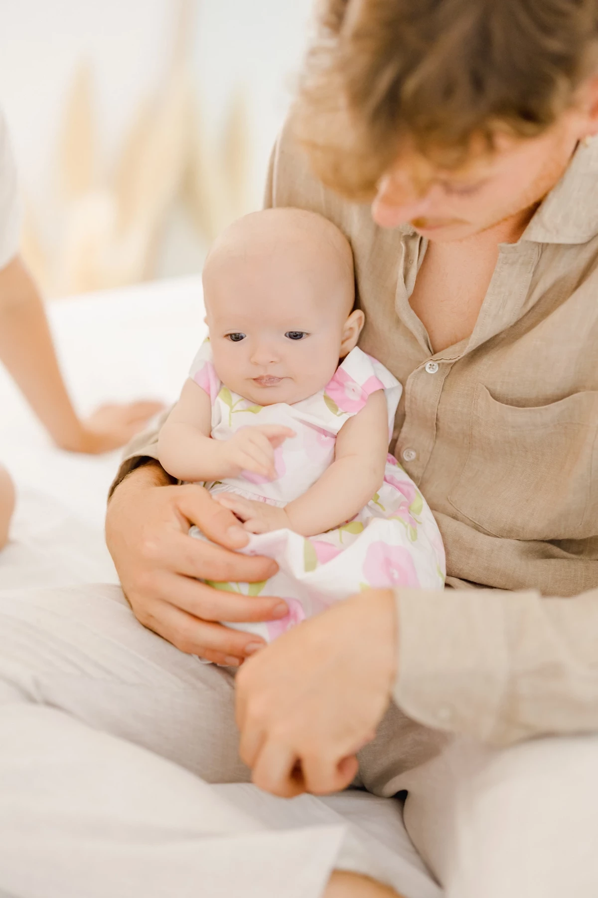 Séance naissance en studio : maman tient tendrement son bébé de 4 mois dans les bras, ambiance douce et lumineuse en tons naturels