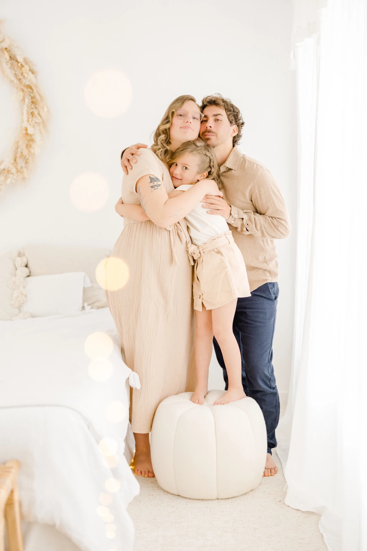 Séance grossesse en famille au studio : parents et enfant enlacés dans une ambiance de tendresse et de douceur naturelle
