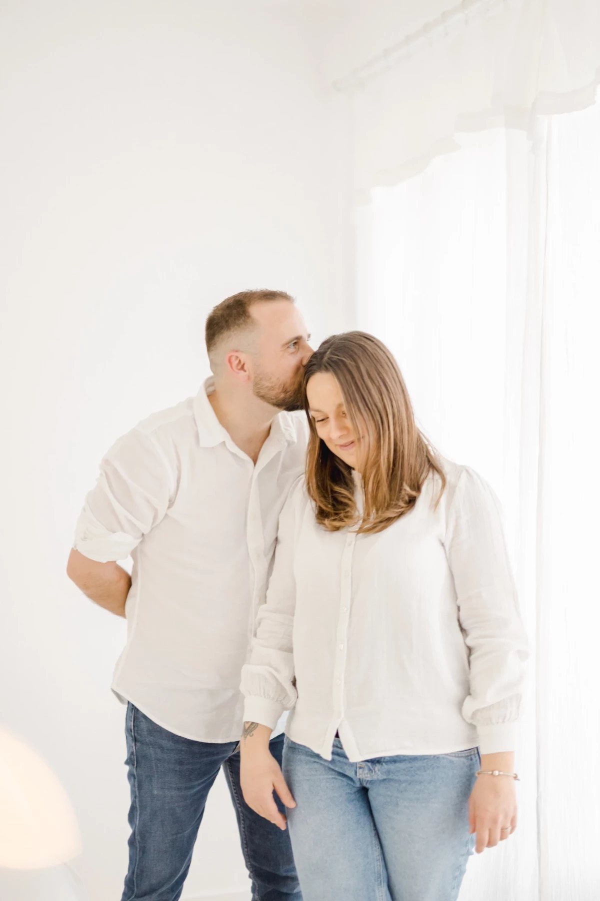 Séance naissance en studio : couple complice dans une ambiance épurée et lumineuse, tendresse et douceur avant l'arrivée de bébé