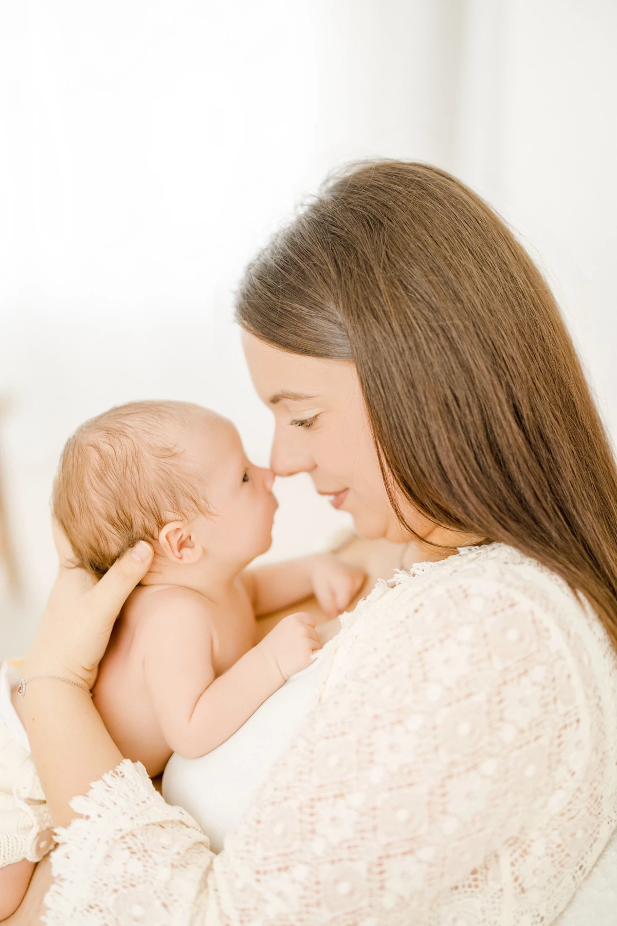Séance allaitement au studio : maman tient son nouveau-né peau à peau dans une lumière naturelle douce et une atmosphère de tendresse infinie