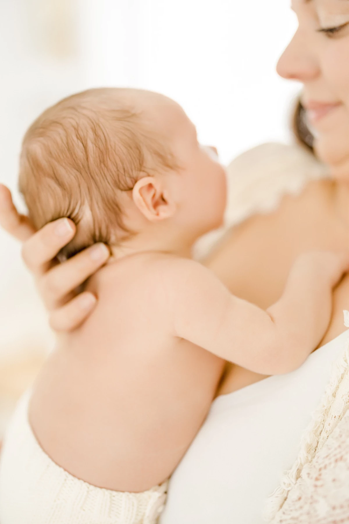 Séance allaitement en studio : maman nourrit son nouveau-né peau à peau dans une lumière naturelle douce et intimiste