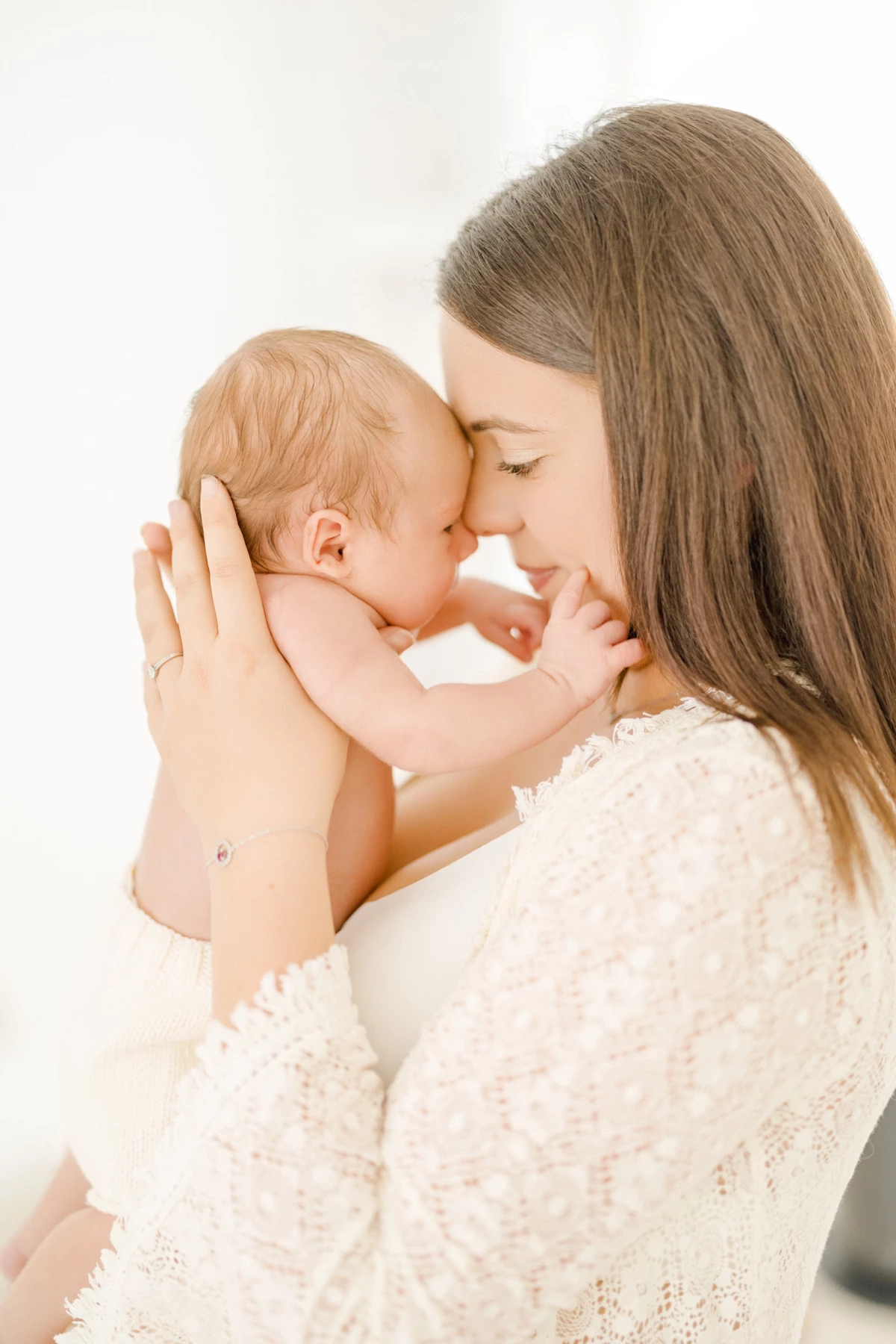 Séance naissance au studio : maman et nouveau-né front contre front dans une lumière naturelle douce, tendresse infinie
