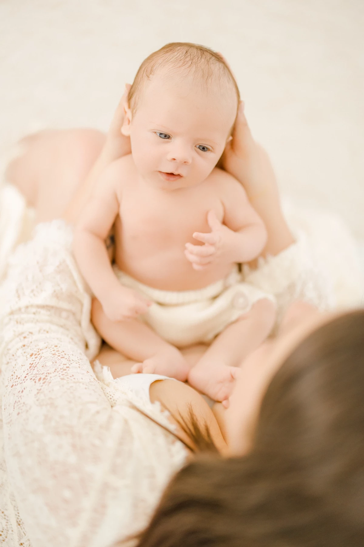 Séance allaitement en studio : maman nourrit son nouveau-né en peau à peau, lumière naturelle douce, tendresse maternelle infinie