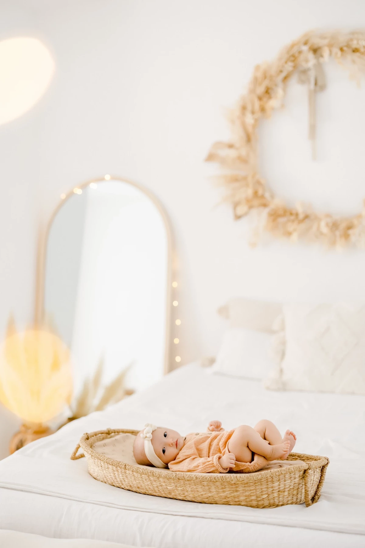 Séance nouveau-né en studio : bébé de 4 mois repose paisiblement dans un panier en osier, ambiance douce et lumineuse.