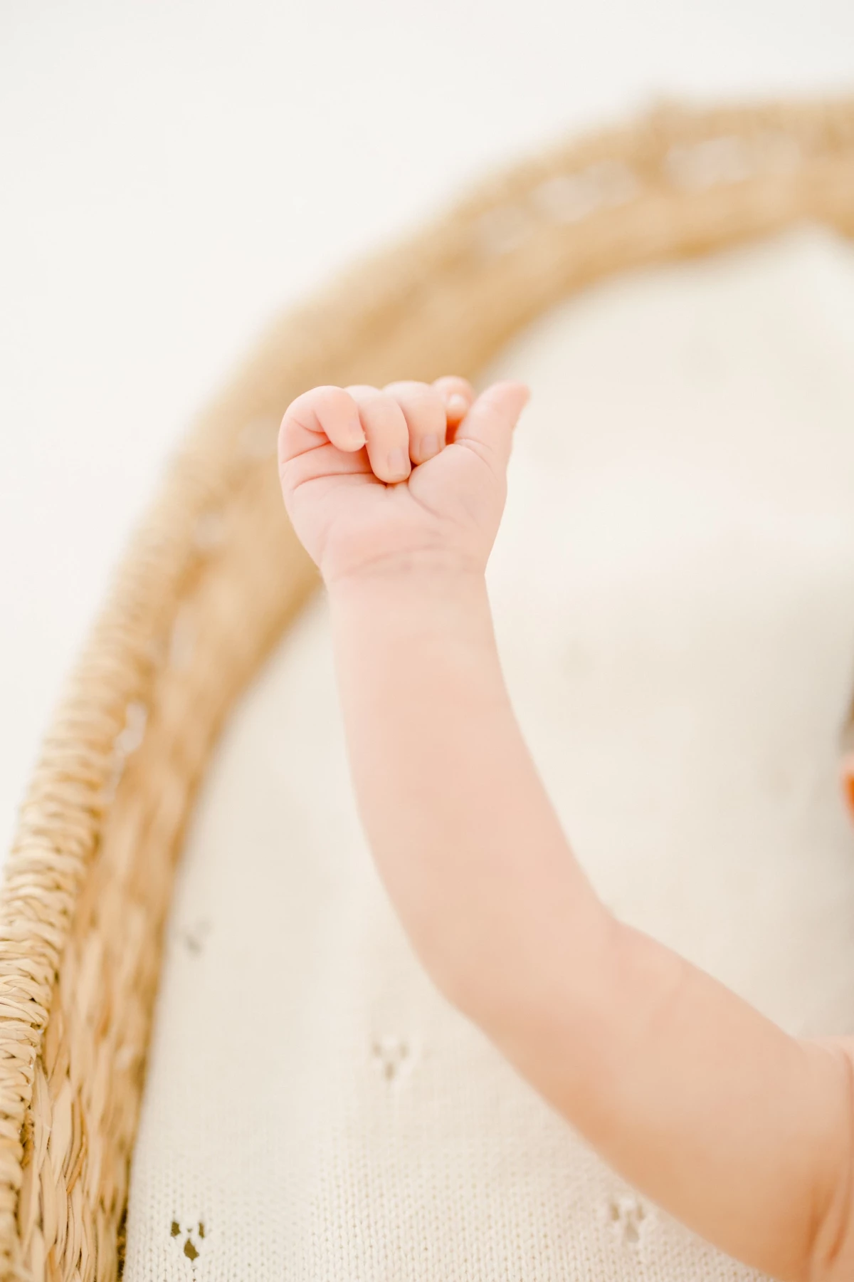 Séance naissance au studio : petit poing de nouveau-né levé, tendresse et fragilité immortalisées dans une lumière douce et naturelle