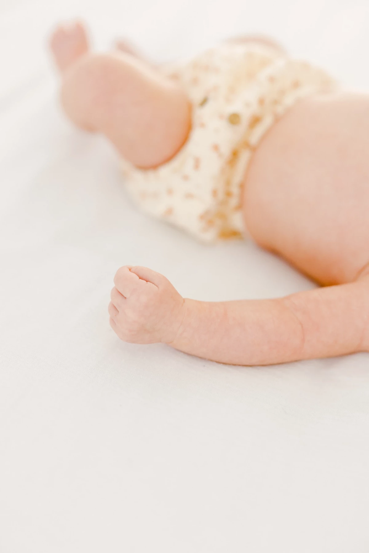 Séance naissance au studio : détail des mains et pieds potelés d'un nouveau-né dans une ambiance de douceur et de tendresse
