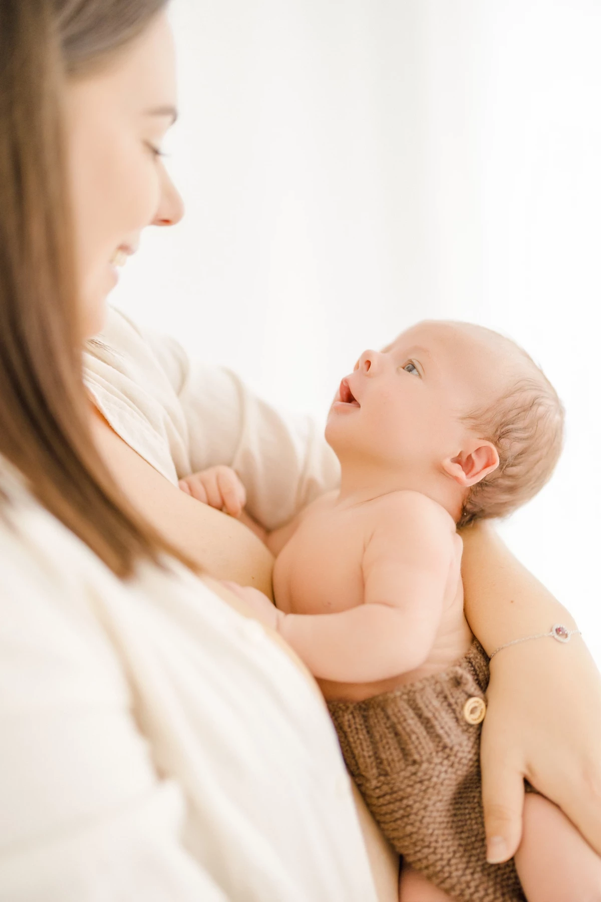 Séance allaitement au studio : maman et nouveau-né peau à peau dans une lumière naturelle douce, instant de tendresse maternelle