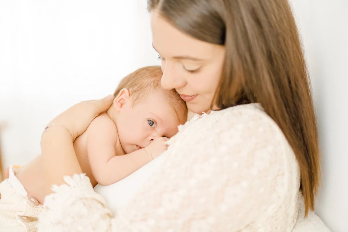 Séance naissance en studio : maman enlace tendrement son nouveau-né en peau à peau dans une lumière douce et naturelle