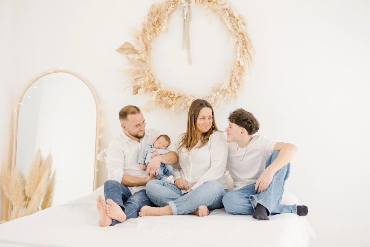 Séance naissance en studio : famille réunie avec nouveau-né et grand frère, partageant un moment de complicité et de douceur