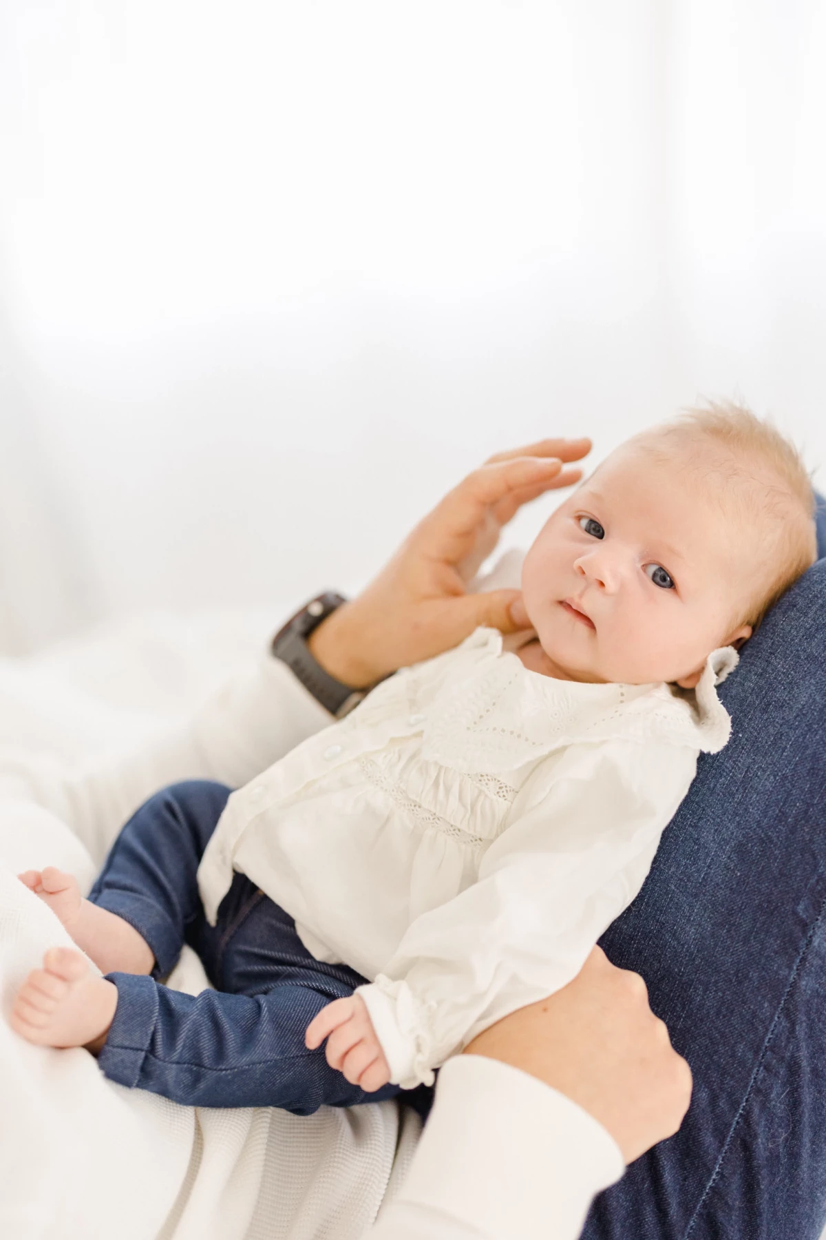Séance naissance au studio : bébé aux yeux clairs blotti contre sa maman dans une lumière douce et naturelle