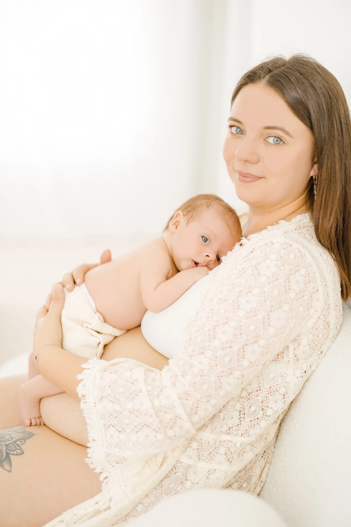 Séance naissance en studio : maman tient son nouveau-né contre elle dans une lumière douce, instant de tendresse et d'amour maternel en Vendée