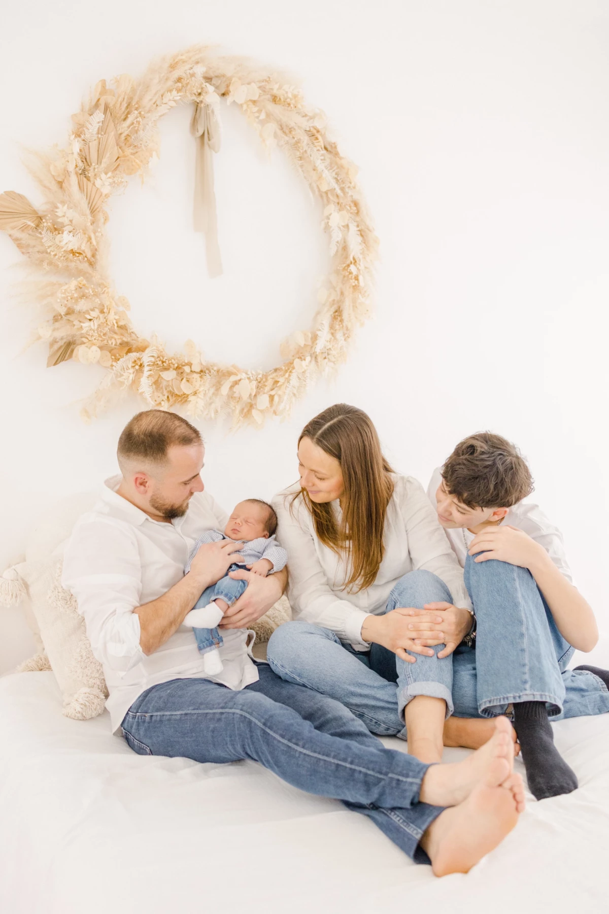 Séance naissance en studio : famille réunie autour de bébé, instant de tendresse et complicité entre parents et grand frère