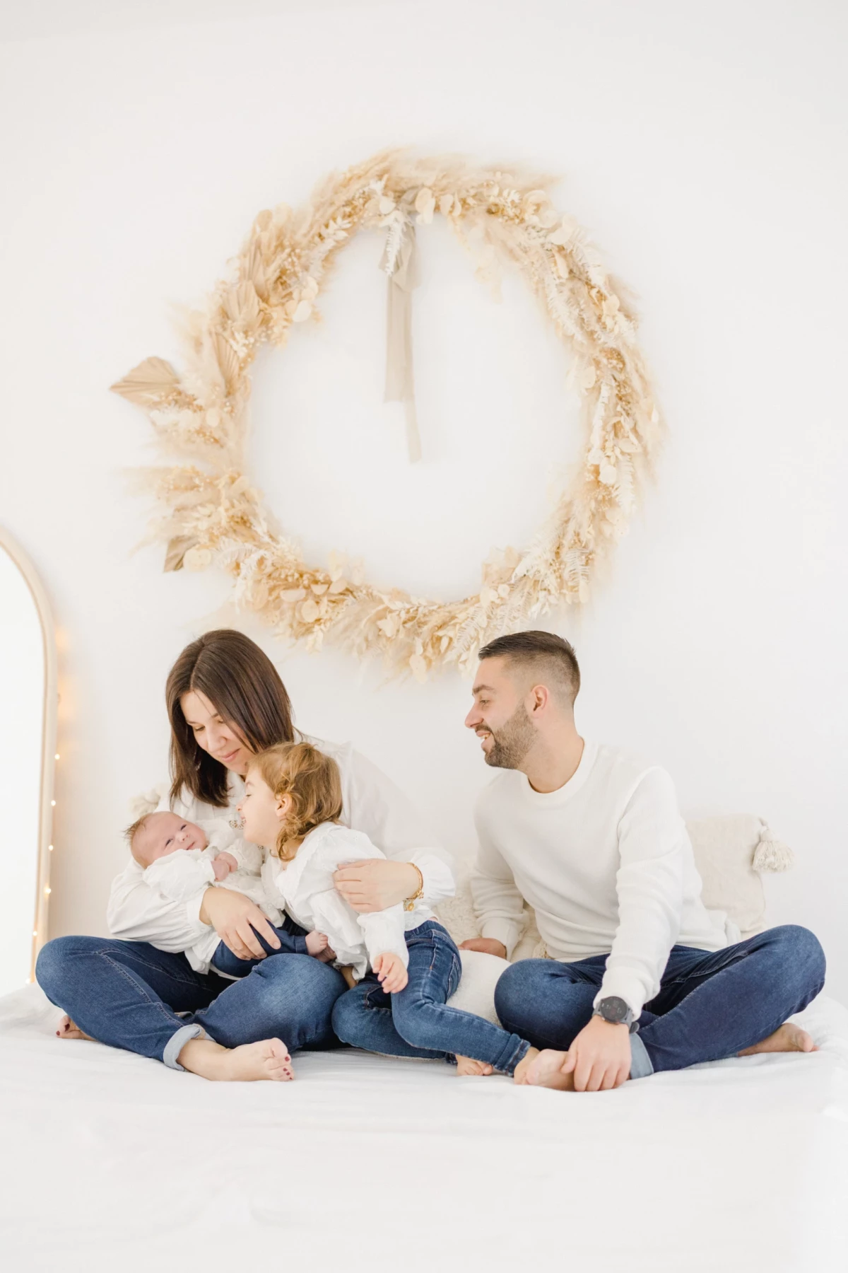 Séance naissance au studio : famille réunie autour de leur nouveau-né, moment de tendresse et complicité dans une ambiance douce