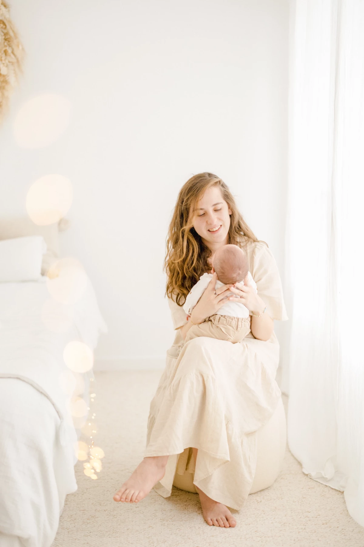 Séance naissance en studio : maman berce son nouveau-né dans ses bras, lumière douce et ambiance épurée, tendresse infinie