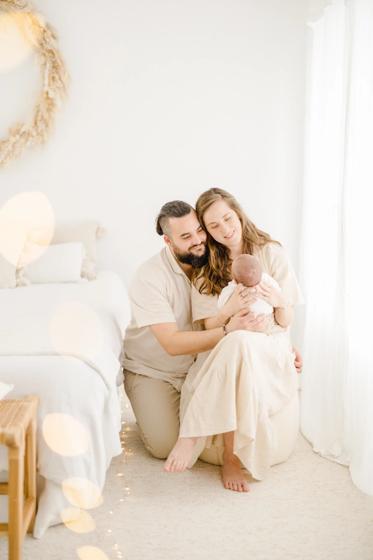 Séance naissance en studio : jeunes parents enlacent leur nouveau-né dans une ambiance de douceur et lumière naturelle