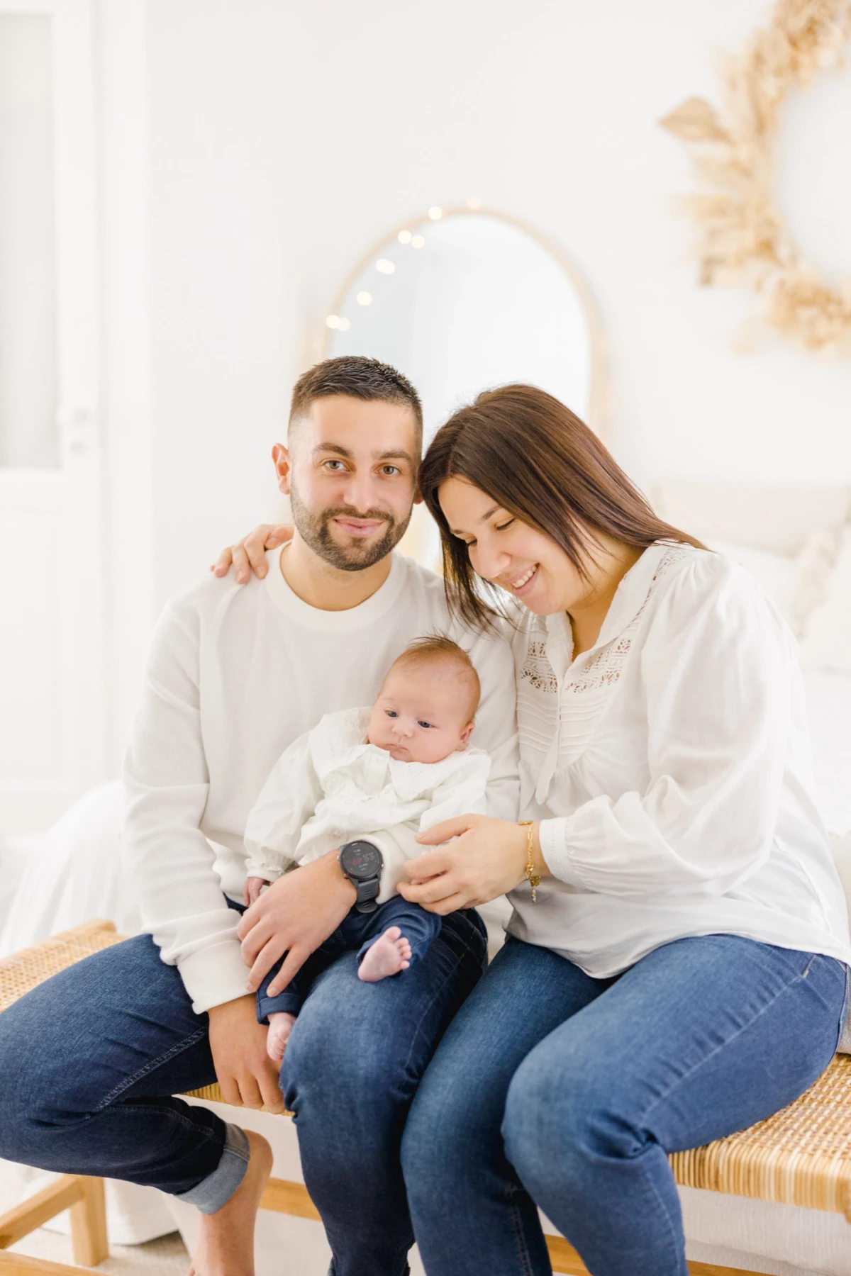 Séance naissance en studio : jeunes parents enlacent tendrement leur nouveau-né dans une ambiance lumineuse et épurée