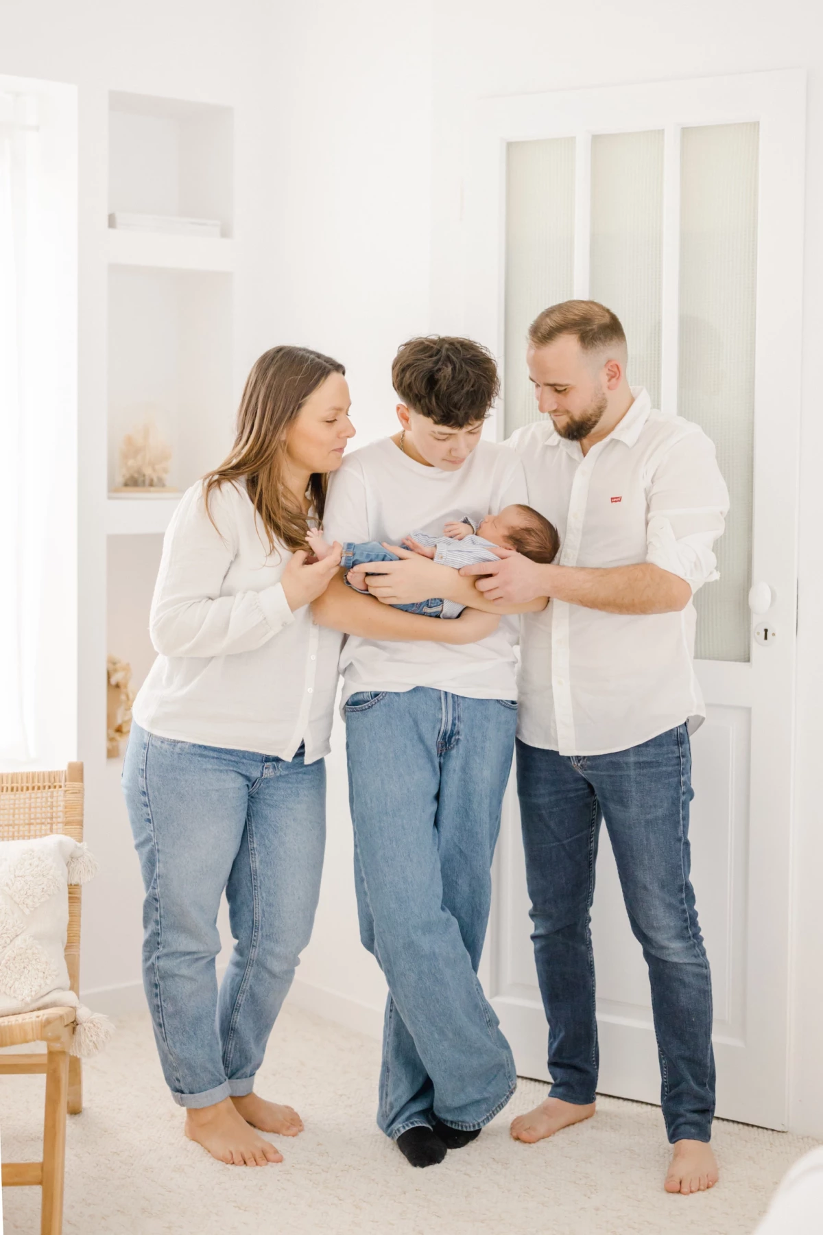 Séance naissance en studio : famille réunie autour du nouveau-né, parents et grand frère partagent un moment de tendresse
