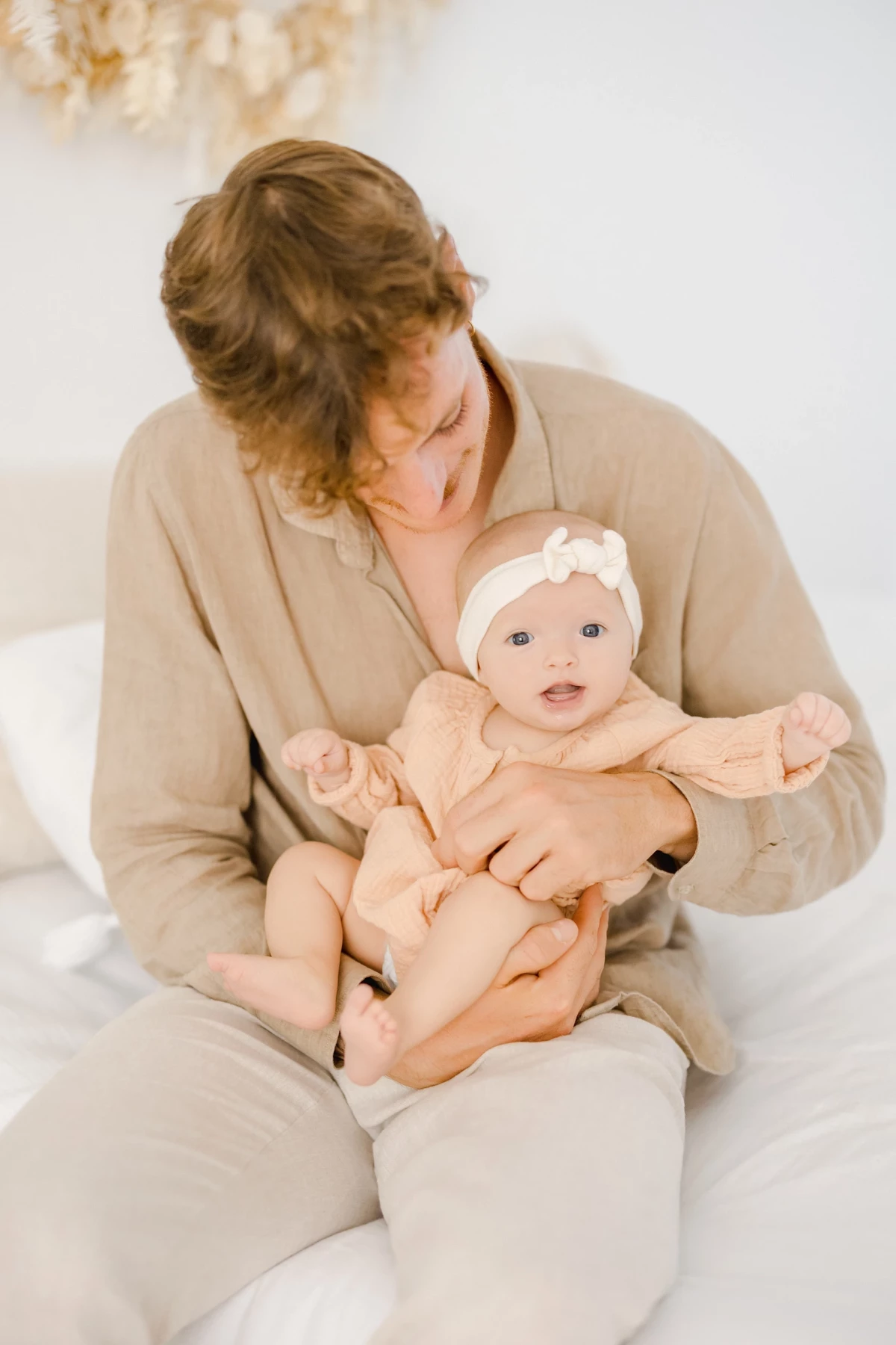 Séance naissance au studio : maman berce son bébé de 4 mois dans une ambiance douce et épurée, tendresse infinie