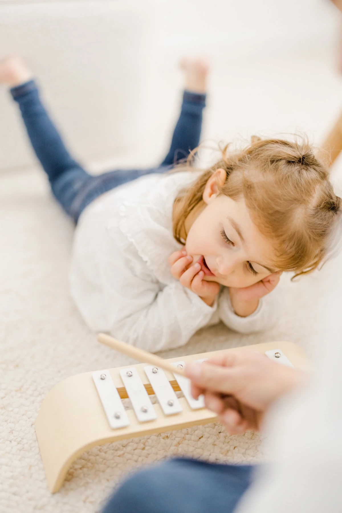 Séance naissance en studio : petite fille souriante joue avec sa maman, moment de complicité et de tendresse familiale