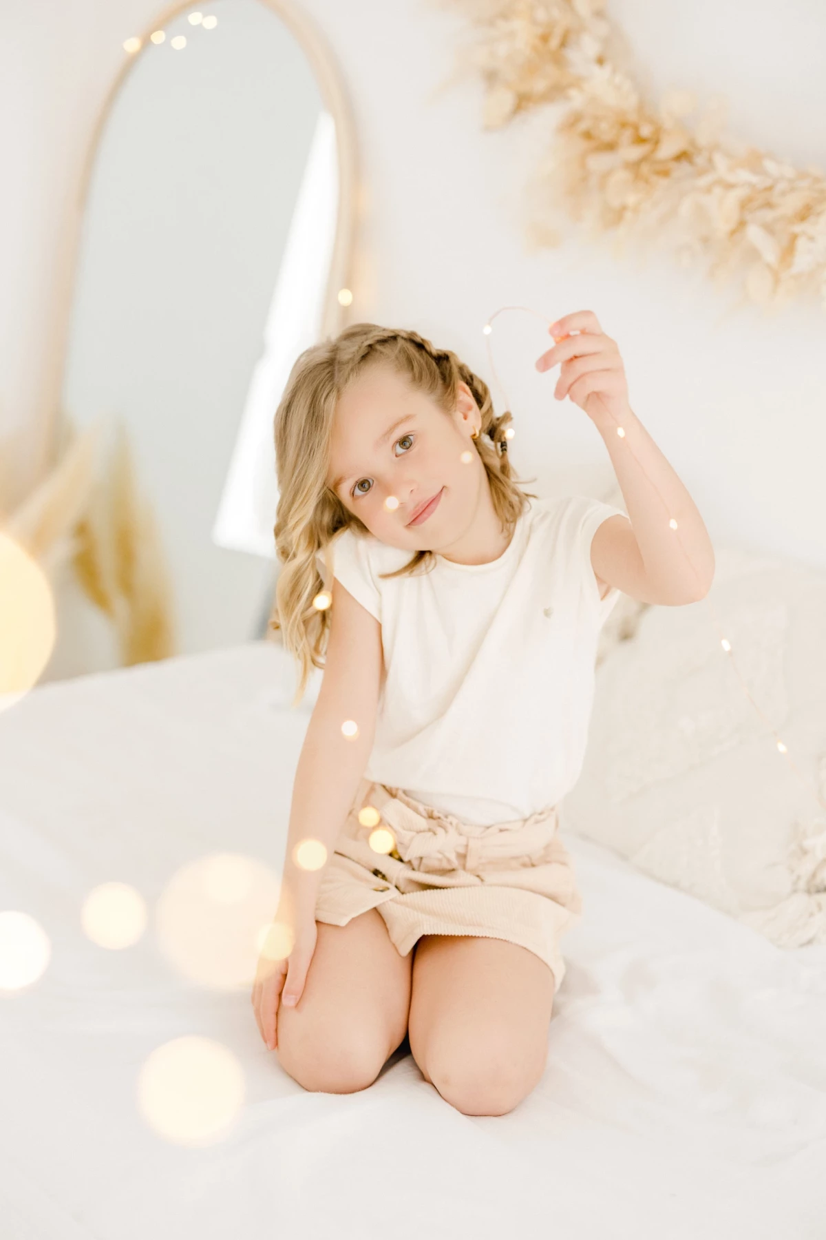 Séance famille en studio : petite fille souriante assise dans un décor blanc épuré, tendresse et douceur naturelle en Vendée