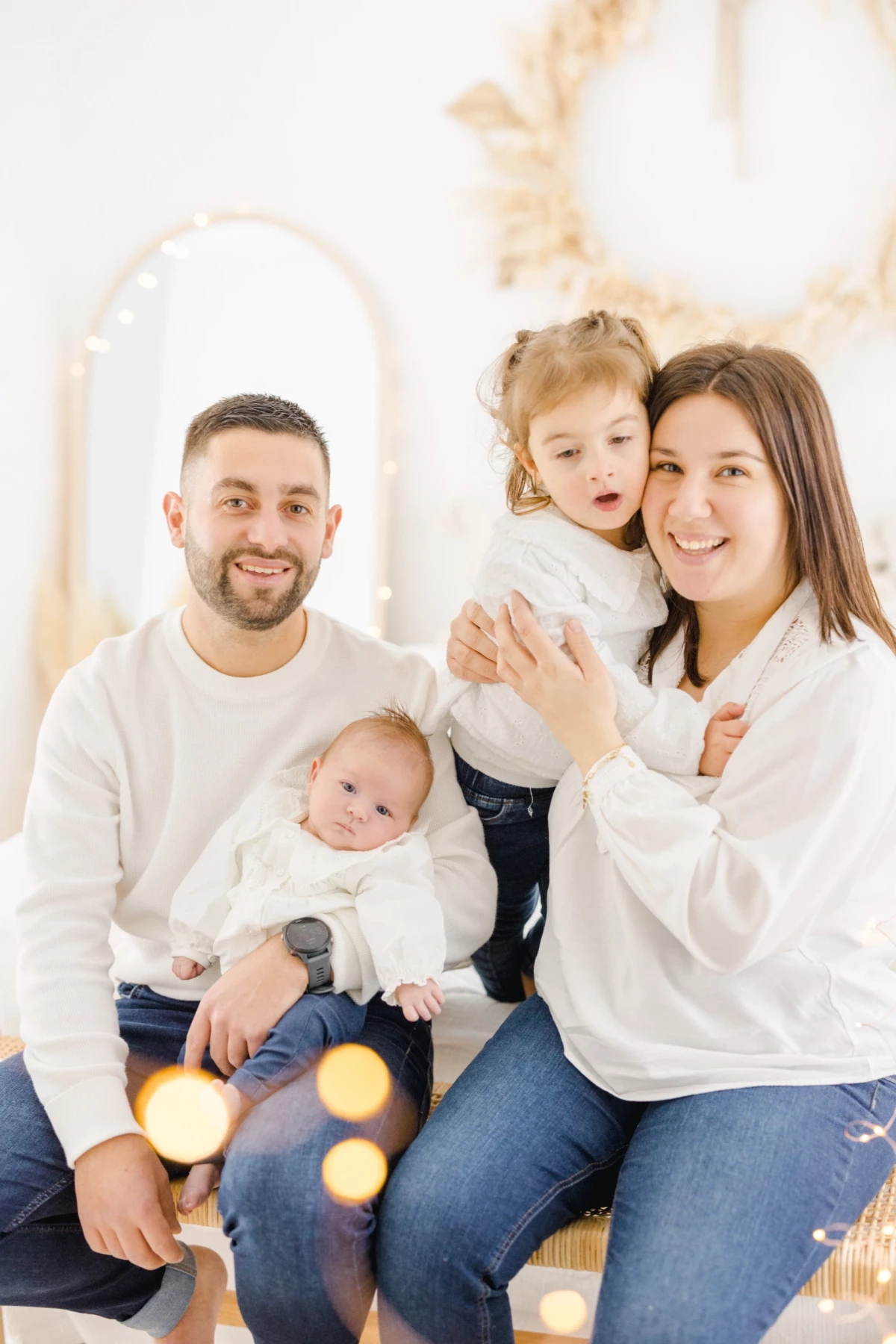 Séance famille au studio : parents et deux enfants partagent un moment de complicité et de tendresse dans une ambiance lumineuse