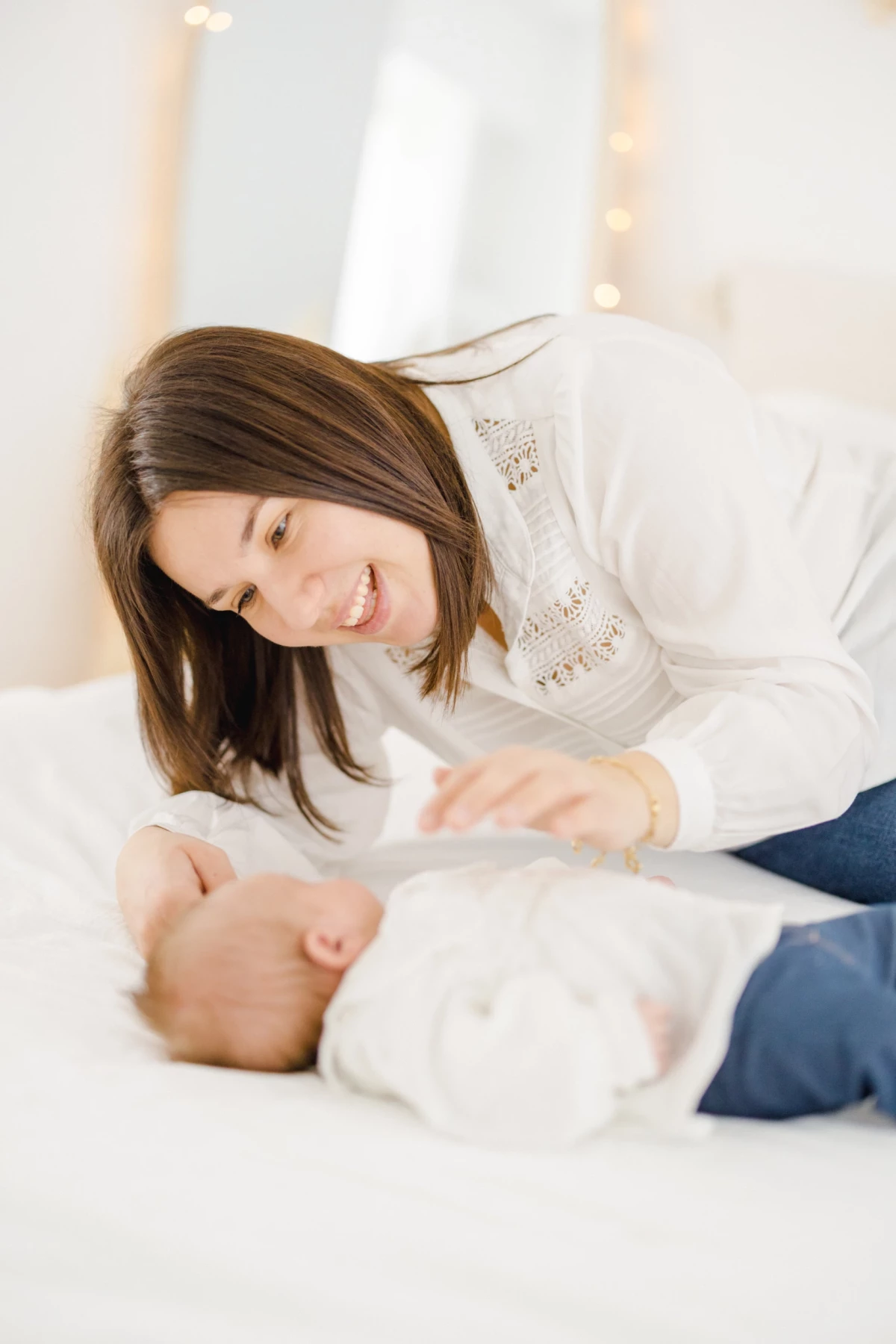 Séance naissance au studio : maman souriante contemple son nouveau-né endormi, instant de douceur et connexion maternelle