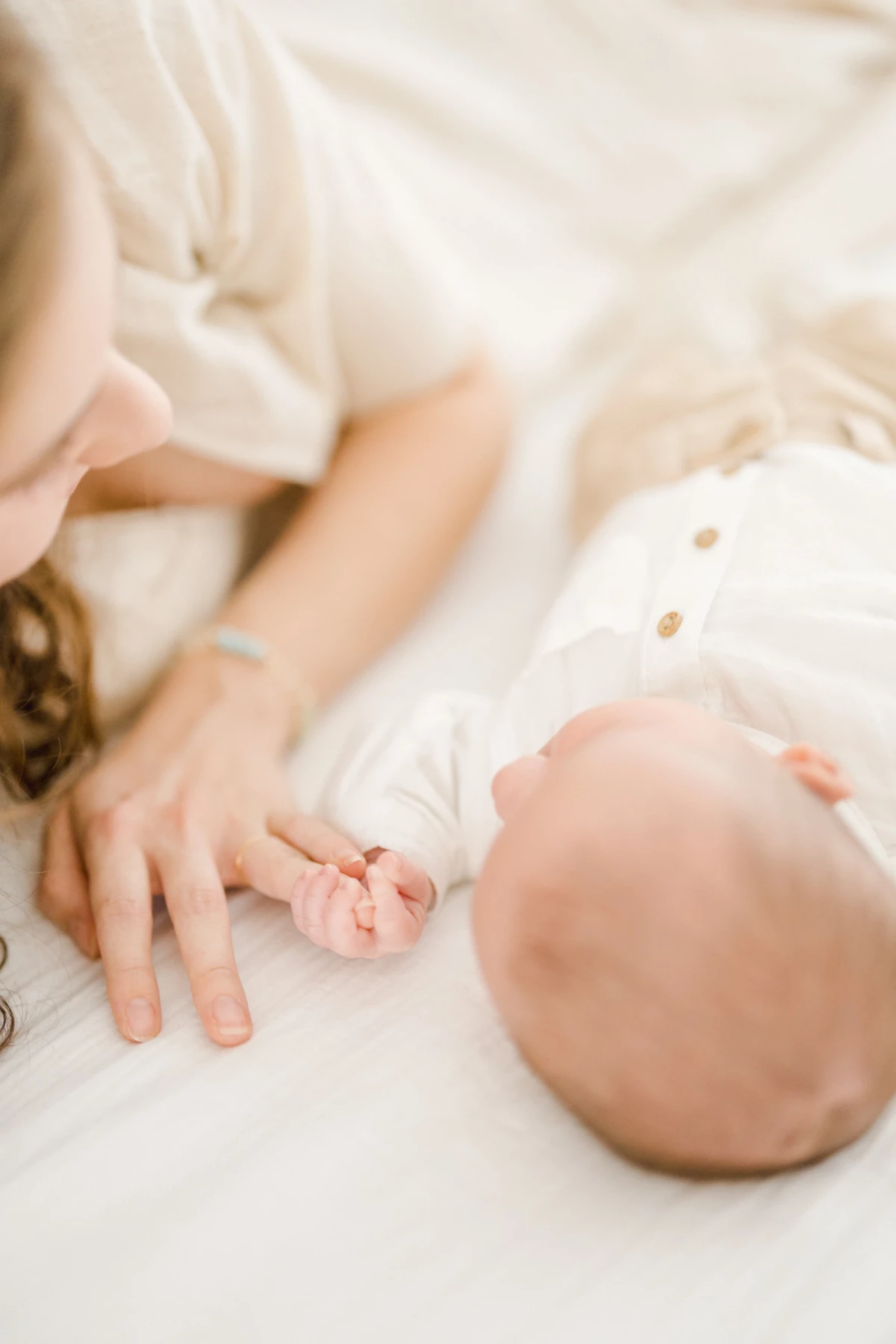 Séance naissance en studio : main de maman tenant délicatement les petits doigts de son nouveau-né dans une atmosphère de tendresse